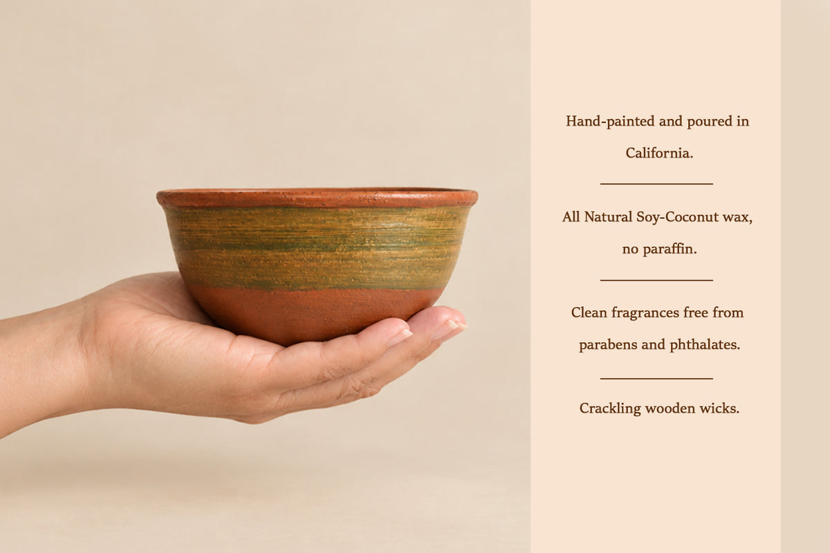 A hand holds a small handmade ceramic bowl with a terracotta base and olive-green glazed band, next to text describing the product's hand-painted creation, soy-coconut wax, and natural fragrance qualities.