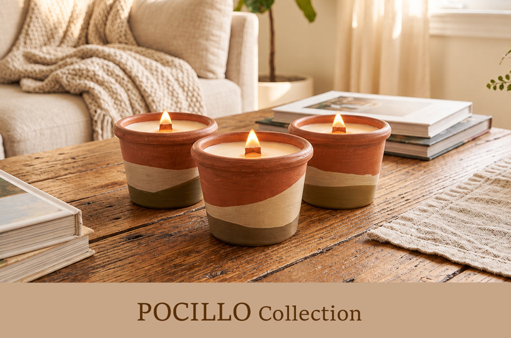 Three lit ceramic candles in terracotta, cream, and olive-green striped tumblers on a rustic wooden table in a cozy living room setting, with a sofa and books in the background. Text overlay at the bottom reads 'POCILLO Collection'.