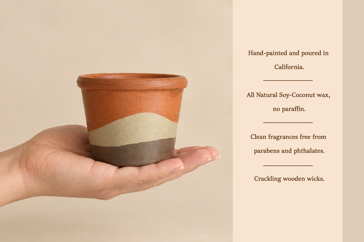 A hand holds a small hand-painted wax candle tin with terracotta, beige, and dark brown wavy stripes. Text on the right lists product features like hand-painting, pouring location, soy-coconut wax, and fragrance claims.